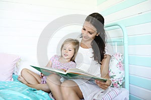 Family reading bedtime. Pretty young mother reading a book to daughter.