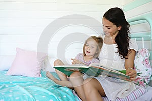 Family reading bedtime. Pretty young mother reading a book to daughter.