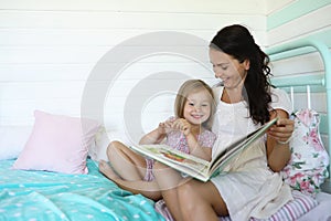 Family reading bedtime. Pretty young mother reading a book to daughter.