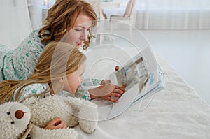 Family reading bedtime. Pretty young mother reading a book to her daughter. Mother reads a fairy tale to her daughter. A