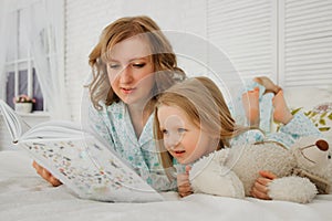 Family reading bedtime. Pretty young mother reading a book to her daughter. Mother reads a fairy tale to her daughter. A