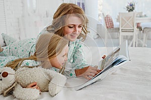 Family reading bedtime. Pretty young mother reading a book to her daughter. Mother reads a fairy tale to her daughter. A