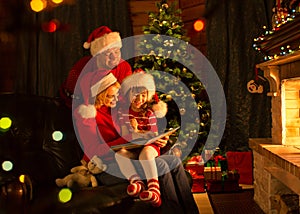 Family reading a book by a Christmas tree in cozy