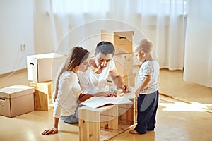 Family reading instruction and assemble furniture together at living room of new apartment pile of moving boxes on