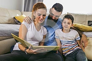 Family reading storybook at home in the living room