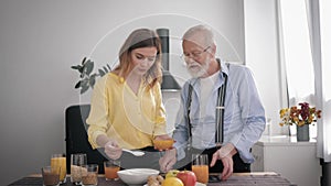 Family relationship, happy peppy old man prepares a delicious breakfast in the kitchen with healthy products, mixes with