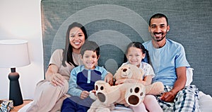 Family, relax on bed and portrait with happiness, teddy bear for comfort and bonding at home together. Mother, father