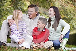 Family relaxing in autumn woodlands