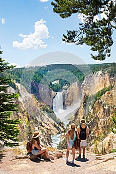 Family relaxing and enjoying beautiful view of waterfall on hiking trip in the mountains.