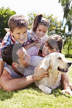 Family Relaxing In Garden With Pet Dog