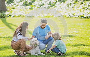 Family relaxing in garden with pet dog. The concept of a happy family. Parents and children on vacation playing together