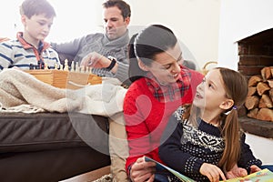 Family Relaxing Indoors Playing Chess And Reading Book