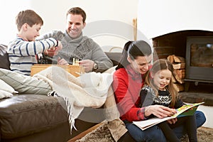 Family Relaxing Indoors Playing Chess And Reading Book photo