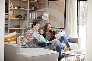 Family Relaxing On Sofa At Home Watching Television