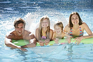 Family Relaxing In Swimming Pool Together