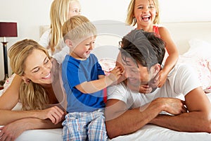 Family Relaxing Together In Bed