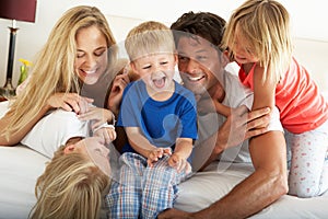 Family Relaxing Together In Bed