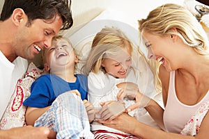 Family Relaxing Together In Bed