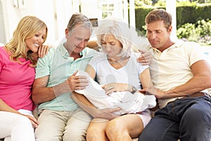 Family Relaxing Together On Sofa With Newborn Baby