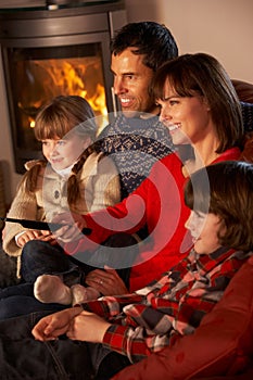 Family Relaxing Watching TV By Cosy Log Fire