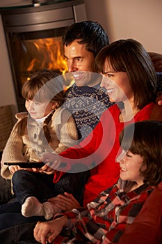 Family Relaxing Watching TV By Cosy Log Fire