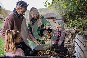 Family removing compost from a composter in garden, and composting kitchen waste in composter. Concept of composting and