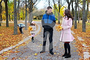Family resting in the autumn park along the path. Beautiful nature and trees with yellowleaves