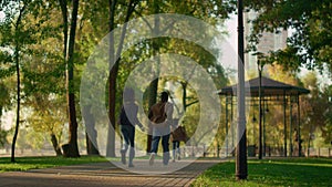 Family resting autumn park running path together rear view. Happy leisure time.