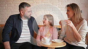 Family Resting in Cafe. Family is Mother, Father and Daughter. People is Sitting at Table. They Are Happy and Smiling