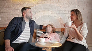 Family Resting in Cafe. Family is Mother, Father and Daughter. People is Sitting at Table. They Are Happy and Smiling