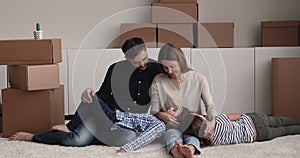 Family resting on floor in unfurnished room at relocation day
