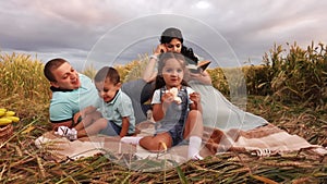 Family resting on picnic in meadow in slow motion