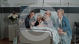 Family and retired man taking selfie with smartphone at visit