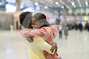 Family reunion in airport. Happy black male hugging excited woman after plane arrival in terminal