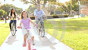 Family Riding Bikes Through Summer Park