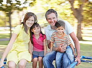 Family Riding On Roundabout In Park