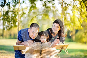 Family riding on a swing in the evening park