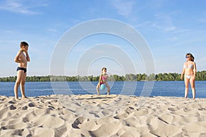 Family on the river bank playing beach volleyball on a sunny, summer day