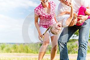 Family romping on field with parents carrying child photo