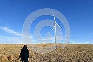 A family running across a field with a Wind turbine in the background across the vast farm land of Alberta, Canada.
