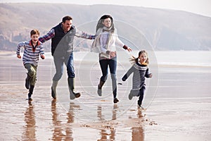 Family Running Along Winter Beach