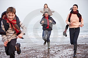 Family Running Along Winter Beach