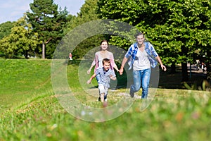 Family running fast in grass on meadow