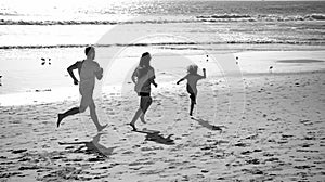 Family running on a sandy beach. Concept of friendly family jogging outdoors. Active parents and people outdoor activity