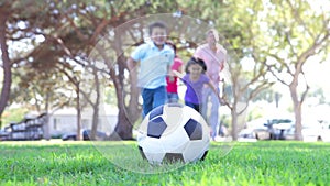 Family Running Towards Soccer Ball And Kicking It