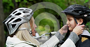 Family, safety and protection while mother and daughter put on their helmets and get ready to ride their bicycles
