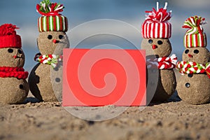Family of sandy Snowmen at tropical beach with blank card.