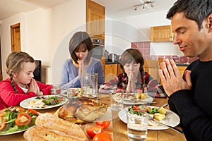 Family Saying Grace Before Eating Lunch photo