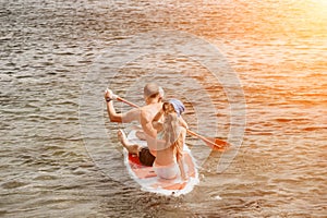 Family sea sup. Young happy father with his son and daughter Floating on a SUP board, paddling in blue sea water. summer