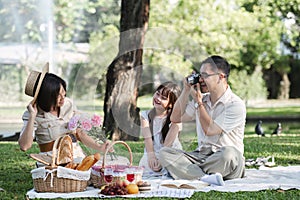 Family of senior couple and daughter picnicking in the park showing love Or reconnect after retirement in a relaxing